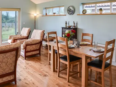 a dining room with a wooden table and chairs at Cedar Lodge in Old Buckenham