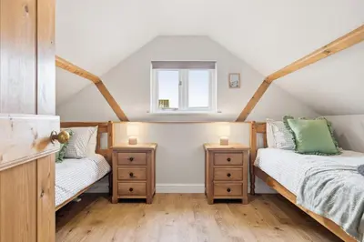 a attic bedroom with two beds and a window at Entire 2 bed coach house in peaceful Norfolk village in Pulham