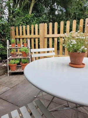a white table and chairs with potted plants on a fence at Entire 2 bed coach house in peaceful Norfolk village in Pulham
