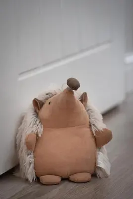 a stuffed animal sitting on the floor next to a wall at Hedgehog Cottage in Bury Saint Edmunds