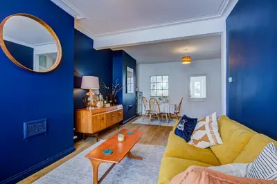 a living room with blue walls and a yellow couch at Cosy house on the seafront - Pass the Keys in Southend-on-Sea