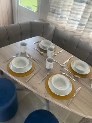 a table with plates and utensils on it at Modern Family Caravan with WiFi at Valley Farm, Clacton-on-Sea in Great Clacton