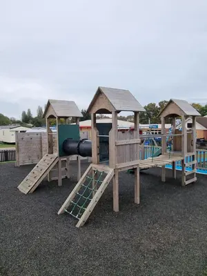 a row of wooden playground equipment with slides at Modern Family Caravan with WiFi at Valley Farm, Clacton-on-Sea in Great Clacton