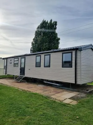 a small white trailer with a tree in the background at Modern Family Caravan with WiFi at Valley Farm, Clacton-on-Sea in Great Clacton