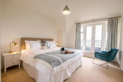 a bedroom with a bed and a chair and a window at Spindrift, Felixstowe in Felixstowe