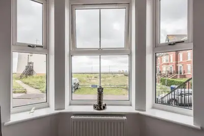 a room with three windows with a radiator in front of it at Spindrift, Felixstowe in Felixstowe