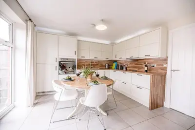 a kitchen with a wooden table and white cabinets at Spindrift, Felixstowe in Felixstowe