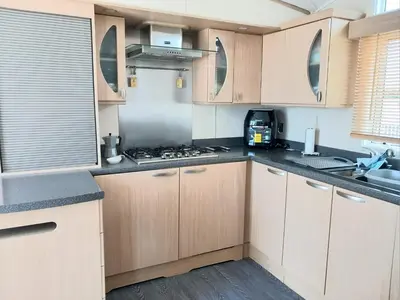 a kitchen with wooden cabinets and a stove top oven at The James Lodge in Little Clacton