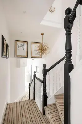 a staircase with white walls and black railings in a house at Beautiful Spacious Beach Home Newly Renovated in Felixstowe