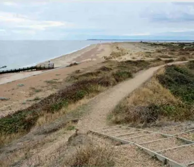 a dirt road leading to a beach next to the ocean at Beautiful Spacious Beach Home Newly Renovated in Felixstowe