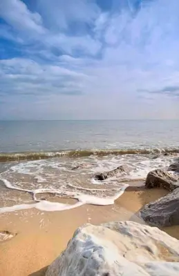 a beach with rocks and the ocean on a cloudy day at Beautiful Spacious Beach Home Newly Renovated in Felixstowe