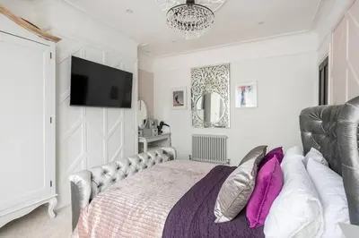 a bedroom with a bed and a tv on the wall at Beautiful Spacious Beach Home Newly Renovated in Felixstowe