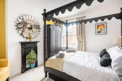 a bedroom with a black and white bed and a mirror at Beautiful Spacious Beach Home Newly Renovated in Felixstowe