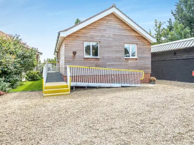 a house with a fence in front of a driveway at Chestnut Lodge in Old Buckenham