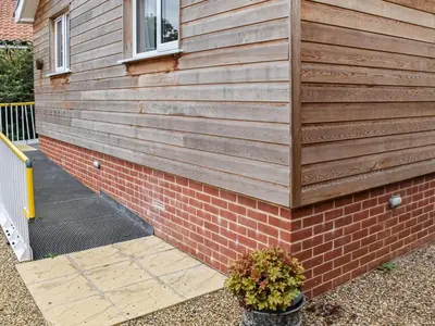 a house with a wooden wall and a brick wall at Chestnut Lodge in Old Buckenham