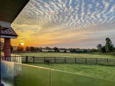 a view of a field with a fence and a sunset at Chestnut Lodge in Old Buckenham