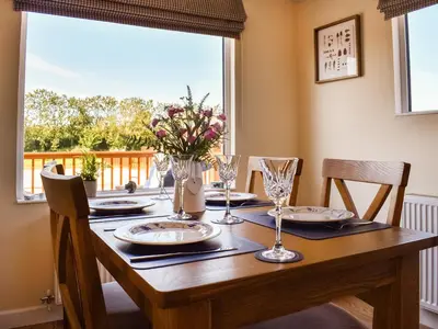 a dining room table with chairs and a large window at Lodge 38 in Stowmarket