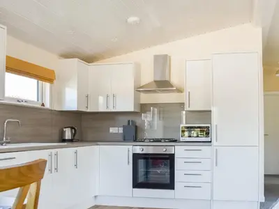 a kitchen with white cabinets and a stove top oven at Lodge 38 in Stowmarket