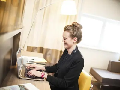 a woman sitting at a desk with a laptop computer at Novotel Ipswich Centre in Ipswich