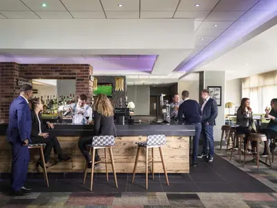 a group of people standing around a bar at Novotel Ipswich Centre in Ipswich