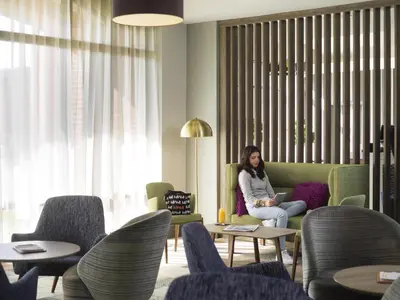 a woman sitting on a couch in a living room at Novotel Ipswich Centre in Ipswich