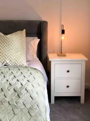a bedroom with a bed and a nightstand with a lamp at Modern flat near train station with free parking in Cambridge