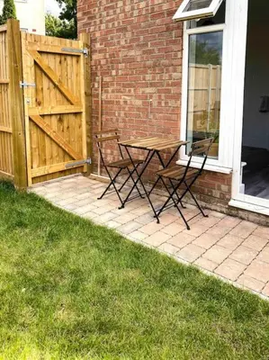 a patio with a table and chairs and a fence at Modern flat near train station with free parking in Cambridge