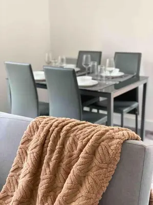 a dining room with a table with chairs and a blanket at Modern flat near train station with free parking in Cambridge