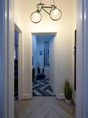 a hallway with white walls and a chandelier at Swanky Seaside Sanctuary w foozeball - Southend in Southend-on-Sea