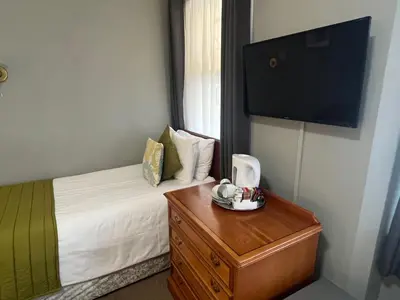 a bedroom with a bed and a dresser and a television at Sorrento Hotel & Restaurant in Cambridge