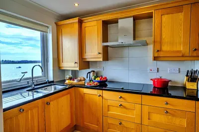 a kitchen with wooden cabinets and a sink and a window at Finest Retreats - Kings Wharf - Luxury Riverside Home in Burnham on Crouch