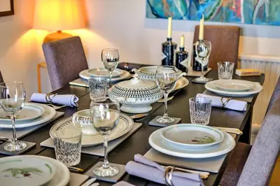 a table with plates and wine glasses on it at Finest Retreats - Kings Wharf - Luxury Riverside Home in Burnham on Crouch