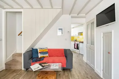 a living room with a couch and a tv at Kingfisher Cottage - Woodbridge in Woodbridge