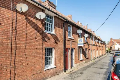 a brick building with white windows on a street at Kingfisher Cottage - Woodbridge in Woodbridge