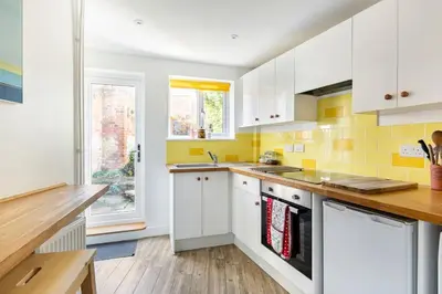 a kitchen with white cabinets and yellow tiles at Kingfisher Cottage - Woodbridge in Woodbridge