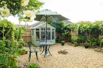 a patio with a table and chairs and an umbrella at 8 Saxonfields in Snape