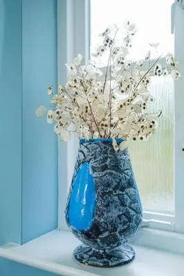 a blue vase with flowers in it on a window sill at 8 Saxonfields in Snape