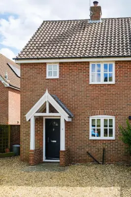 a red brick house with a black door at 8 Saxonfields in Snape