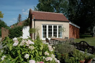 a small house with a table and chairs and flowers at Field Cottage Bed and Breakfast in East Harling