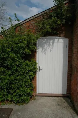 a white garage door in a brick building at Field Cottage Bed and Breakfast in East Harling