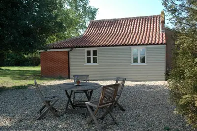 a table and chairs in front of a house at Field Cottage Bed and Breakfast in East Harling