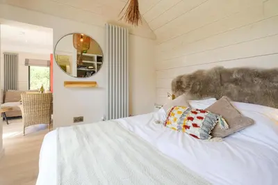 a bedroom with a white bed and a mirror at Mission Lodge in Thorpeness