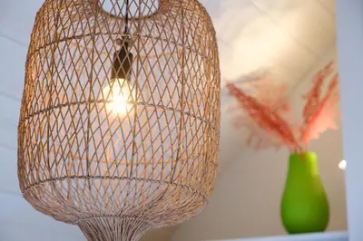 a cage light hanging from a ceiling with a green vase at Mission Lodge in Thorpeness