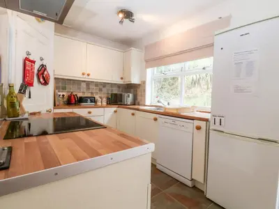 a kitchen with white cabinets and a wooden counter top at The Pink House in Felixstowe