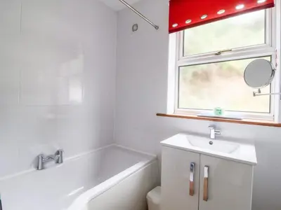 a bathroom with a tub and a sink and a mirror at The Pink House in Felixstowe