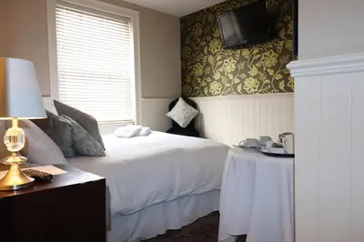 a bedroom with a bed and a table and a tv at The New Boar in Theydon Bois