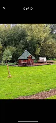 a red barn in a field of green grass at Lake View Lodges The Melford in Long Melford