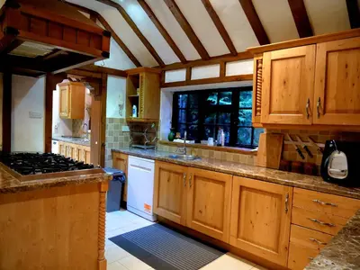 a large kitchen with wooden cabinets and a stove at Beautiful cottage in Brentwood in Kelvedon Hatch