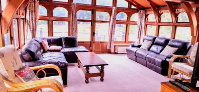 a living room with couches and tables in a room with windows at Beautiful cottage in Brentwood in Kelvedon Hatch