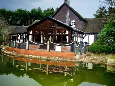 a house with a reflection in a body of water at Beautiful cottage in Brentwood in Kelvedon Hatch